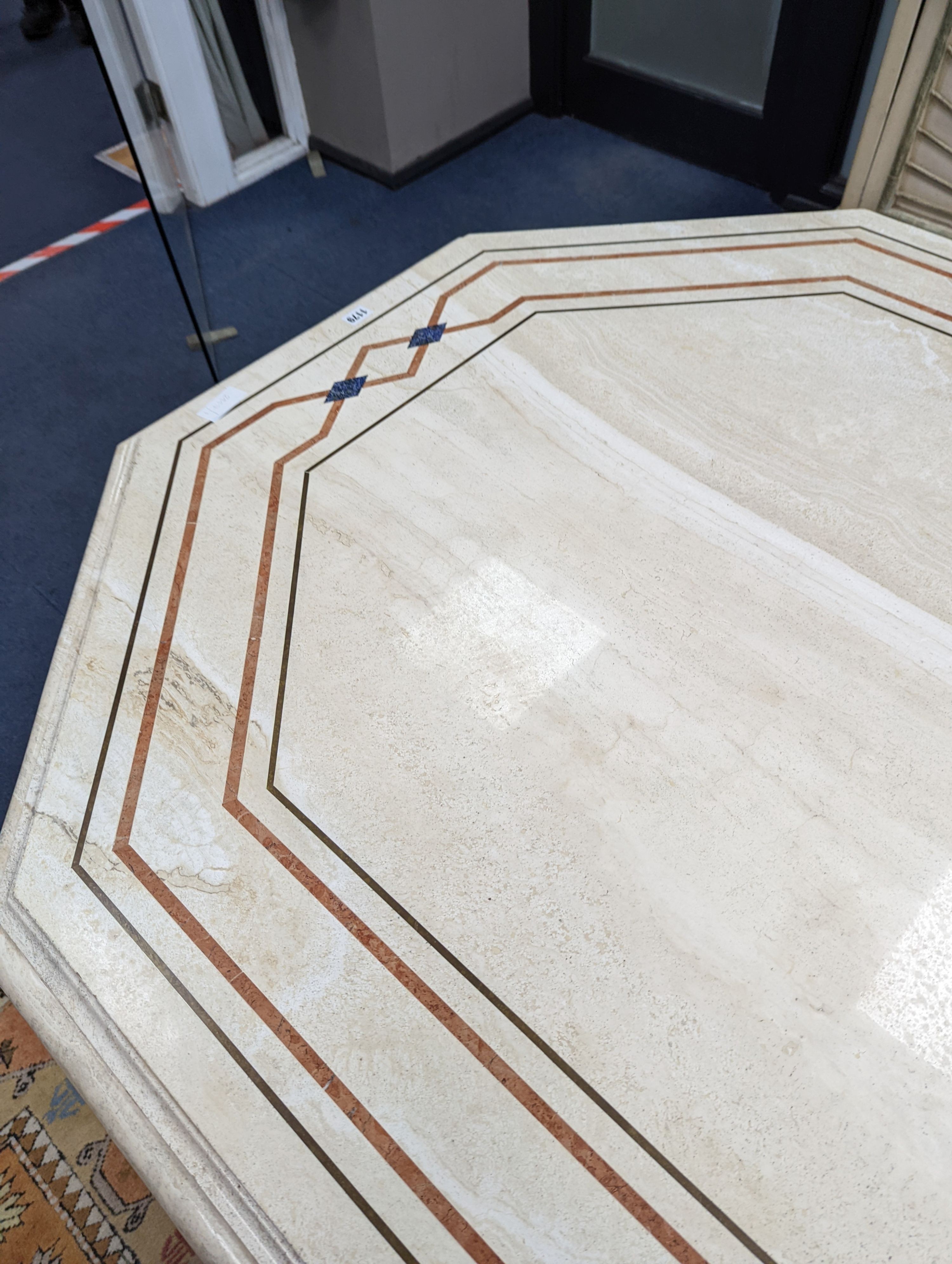 A Travertine marble dining table of elongated ocgtagonal form on twin octagonal column supports, length 260cm, depth 120cm, height 74cm